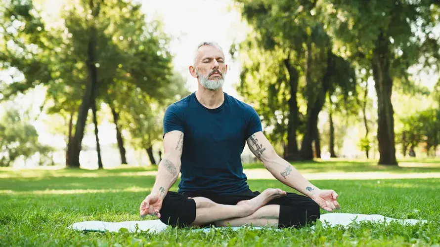 Persona meditando al aire libre en posición de loto