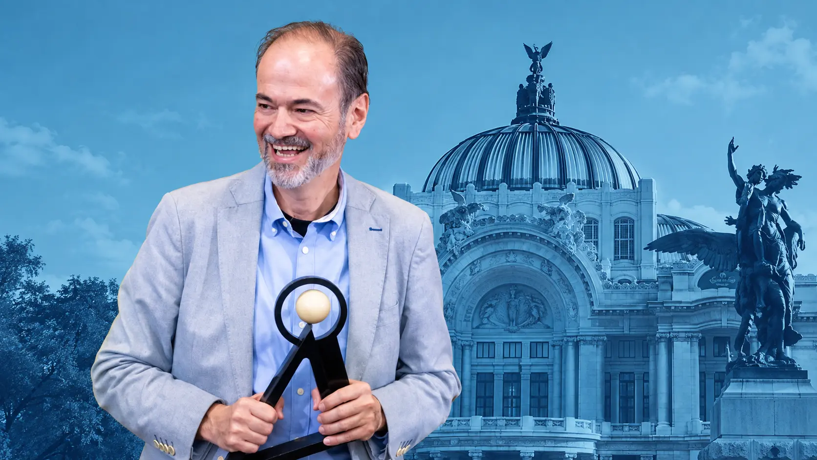 Juan Villoro sonríe mientras sostiene el Premio Internacional Carlos Fuentes 2026, con una composición en tonos azules del Palacio de Bellas Artes al fondo.