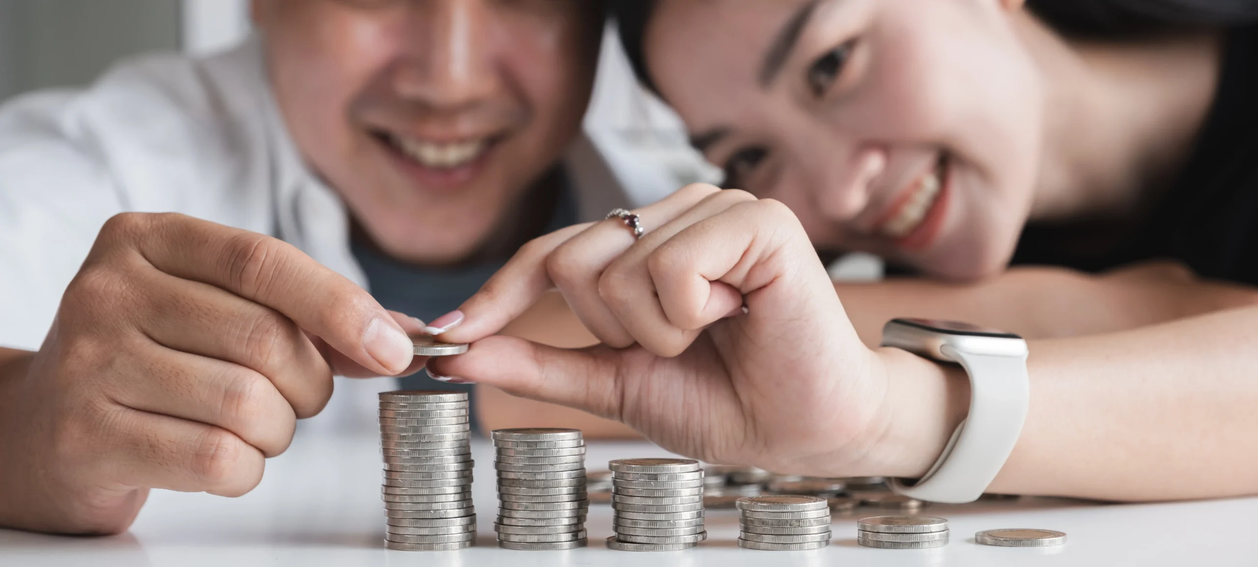Pareja organizando monedas como representación del ahorro y el bienestar financiero.