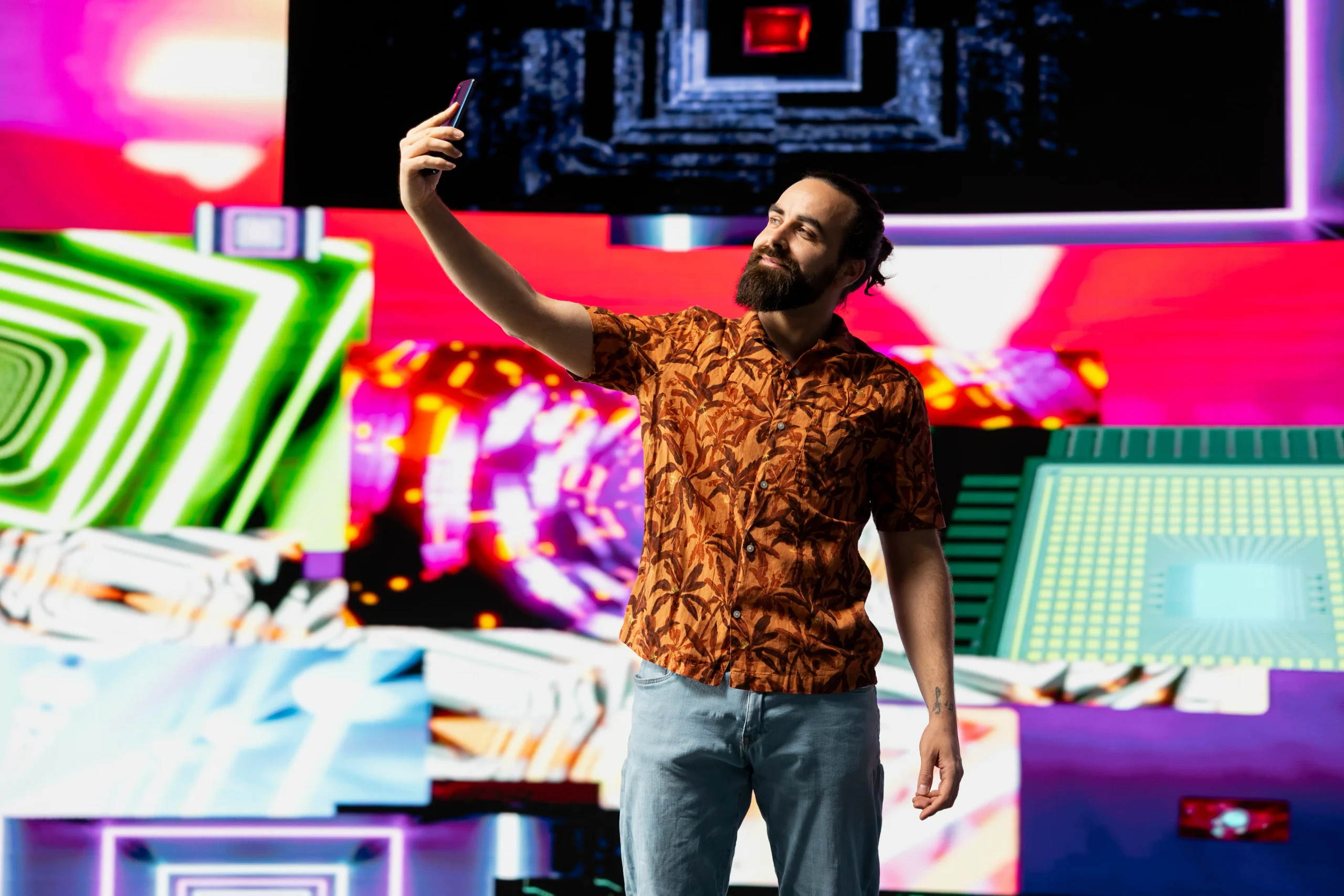 Creador de contenido tomándose una fotografía con su teléfono frente a un escenario digital.